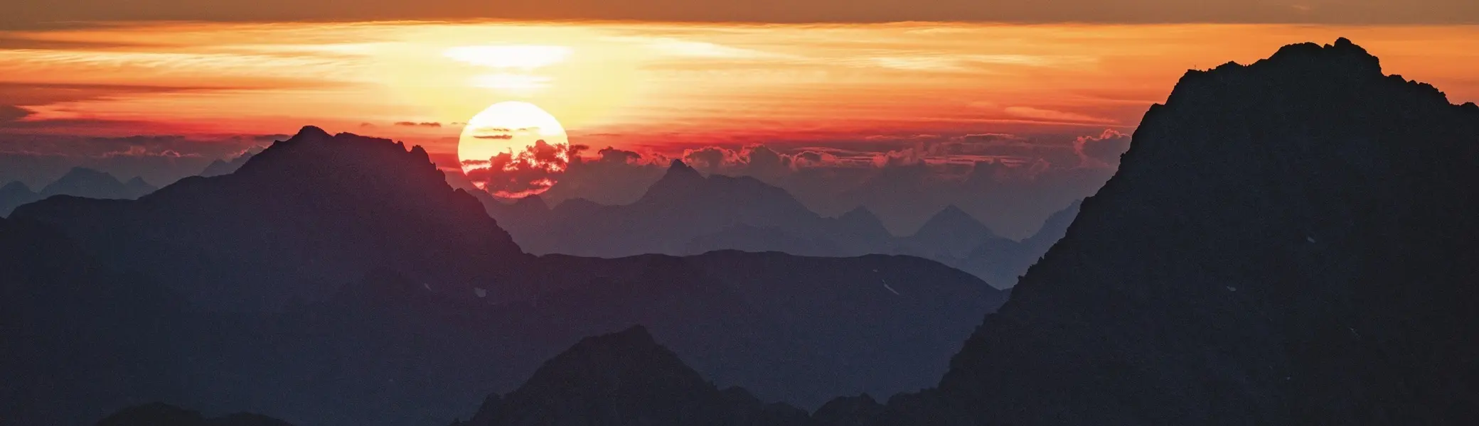 Sonnenuntergang über einer Berglandschaft im Ötztal mit silhouettenhaften Gipfeln und orange-rotem Himmel. | © Michael Heidenfelder