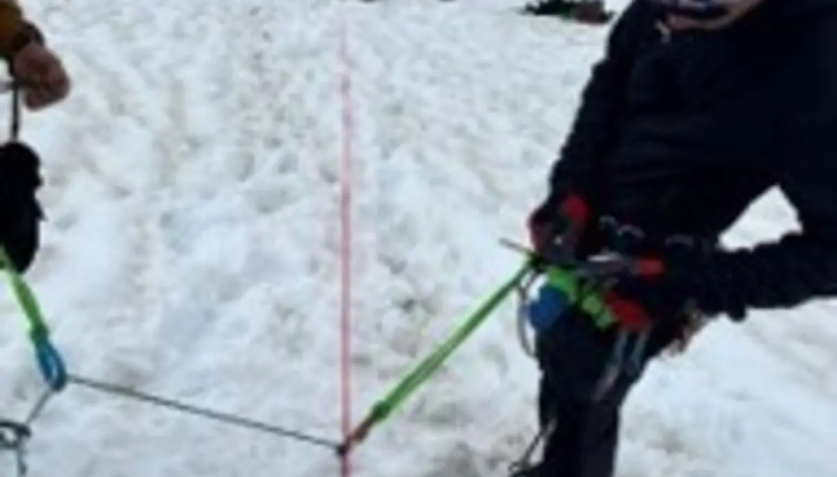 Mehrere angeseilte Personen üben auf einem steilen Schneehang den Umgang mit Seil- und Sicherungstechnik. Ein rotes Seil verläuft über den Schnee zwischen den Teilnehmenden. | © P.J.Müller