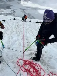 Mehrere angeseilte Personen üben auf einem steilen Schneehang den Umgang mit Seil- und Sicherungstechnik. Ein rotes Seil verläuft über den Schnee zwischen den Teilnehmenden. | © P.J.Müller