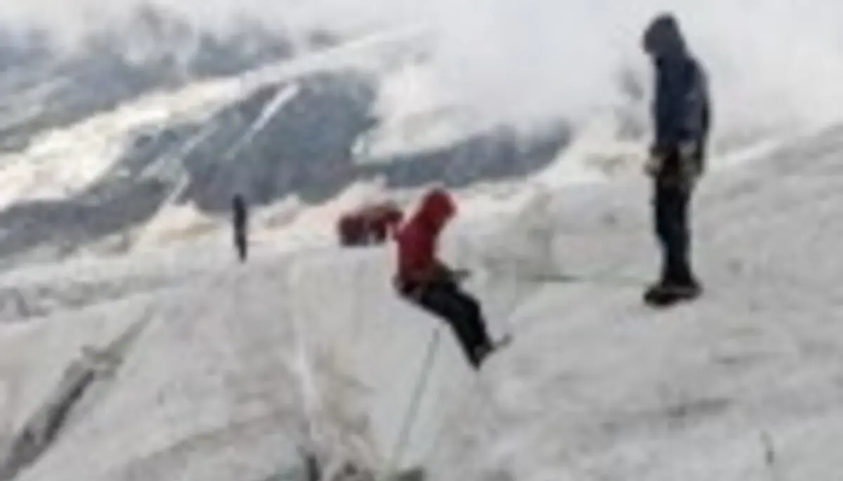Mehrere Personen mit Hochtourenausrüstung üben auf einem Gletscher den Umgang mit Eis und Sicherungstechniken. Eine Person bewegt sich über eine Eisformation, während andere die Übung beobachten. | © P.J.Müller