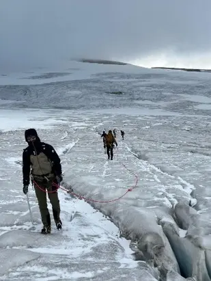 Angeseilte Gruppe bewegt sich über einen Gletscher mit sichtbaren Gletscherspalten. Im Vordergrund führt eine Person die Seilschaft durch die hochalpine Eislandschaft. | © P.J.Müller