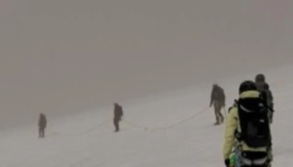 Angeseilte Seilschaft bewegt sich mit Steigeisen über ein weites Schneefeld bei eingeschränkter Sicht im Hochgebirge. | © P.J.Müller
