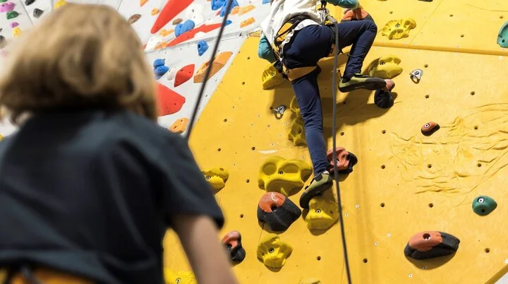 Eine Trainerin sichert ein junges Mädchen in einer Kletterhalle | © DAV / Jens Klatt